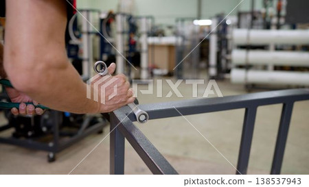 Worker hands using a wrench to assemble a metal frame in a factory Worker hands using a wrench to assemble a metal frame in a factory 138537943