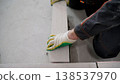 A construction worker's gloved hand laying an autoclaved aerated concrete block to build an interior wall. 138537970