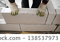 Construction worker in gloves placing a large aerated concrete block while building a wall at a construction site. 138537973