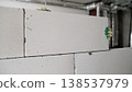 Builder laying a large white aerated concrete block on an interior partition wall. 138537979