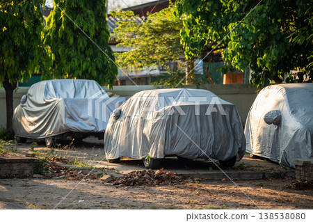 Cars parked on street covered in anti-heating waterproof cover shields, protection for vehicle. Cars parked on street covered in anti-heating waterproof cover shields, protection for vehicle. 138538080