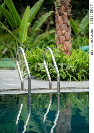 Luxury resort open-air poolside surrounded by greenery and palm trees, comfortable area for rest. Luxury resort open-air poolside surrounded by greenery and palm trees, comfortable area for rest. 138538097