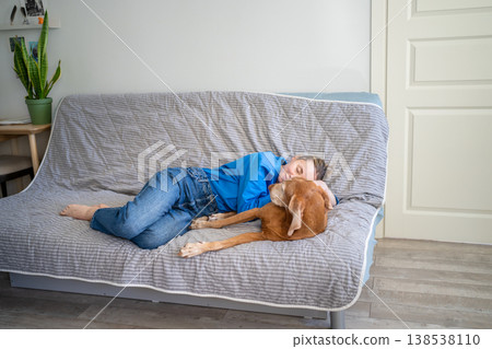 Unconditional love of dog. Relaxed woman gently hug dog on sofa. Animal adoption for lonely female 138538110