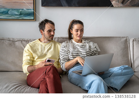 Positive married couple husband and wife choosing hotels online and booking holiday trip on laptop. Positive married couple husband and wife choosing hotels online and booking holiday trip on laptop. 138538128