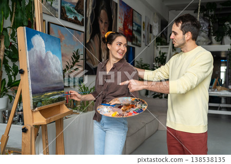 Caring husband showing interest in wife's painting hobby, praises woman painter talent and skills. Caring husband showing interest in wife's painting hobby, praises woman painter talent and skills. 138538135