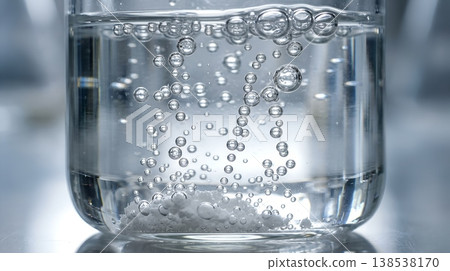 White powder or effervescent tablet dissolving in clear liquid, releasing streams of tiny bubbles, representing solubility and chemical reactions 138538170