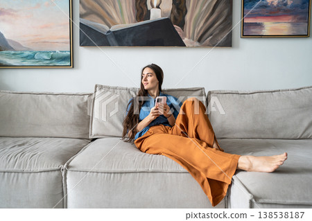 Thoughtful calm woman artist relaxing on couch at home distracted by thoughts looking at window. Thoughtful calm woman artist relaxing on couch at home distracted by thoughts looking at window. 138538187