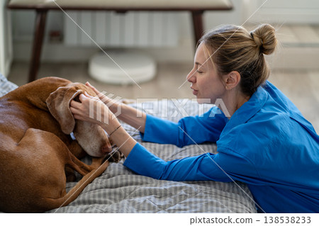 Cheerful mature woman owner talking with pet, stocking dog head saying nice words to beloved pet. Cheerful mature woman owner talking with pet, stocking dog head saying nice words to beloved pet. 138538233