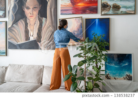 Successful woman painter arranging wall exhibition at studio loft apartment, displaying own artworks Successful woman painter arranging wall exhibition at studio loft apartment, displaying own artworks 138538237