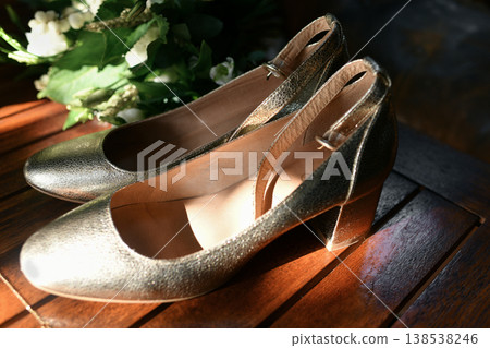Golden bridal shoes on wooden table with greenery sunlight shine Golden bridal shoes on wooden table with greenery sunlight shine 138538246