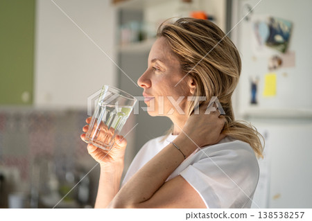 Happy relaxed woman enjoying drinking refreshing water from glass in early morning, healthy habit. Happy relaxed woman enjoying drinking refreshing water from glass in early morning, healthy habit. 138538257