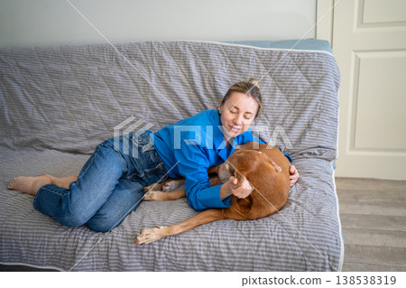 Loving mature woman pet owner relaxing on couch with beloved dog, gently petting moody sleepy doggy. Loving mature woman pet owner relaxing on couch with beloved dog, gently petting moody sleepy doggy. 138538319