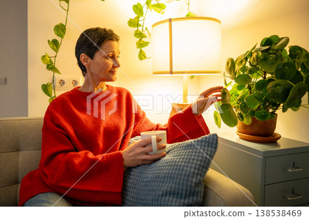 Positive relaxed senior woman enjoys slow life and cozy evening at home while resting on couch. Positive relaxed senior woman enjoys slow life and cozy evening at home while resting on couch. 138538469