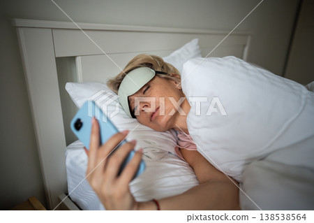 Dreaming sleepy woman phone addict procrastinating morning time in bed with smartphone scrolling. Dreaming sleepy woman phone addict procrastinating morning time in bed with smartphone scrolling. 138538564