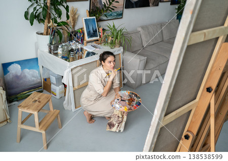 Craftswoman looking at painting, thinking on composition and colors, creative art hobby process. 138538599