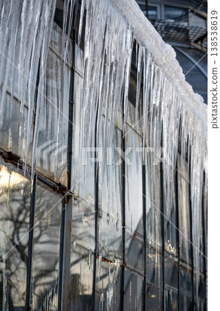 Glasshouse roof covered with huge icicles during cold winter season outdoors. Spring thaw.  138538619