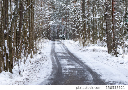 Countryside roadway surrounded by trees forest covered in snow on cold winter day. Countryside roadway surrounded by trees forest covered in snow on cold winter day. 138538621
