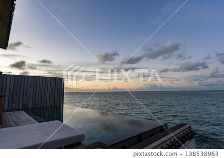 Evening view from the terrace of an overwater villa with a pool in the Maldives 138538963