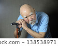 A bearded old man is doing rehabilitation indoors using a cane. 138538971