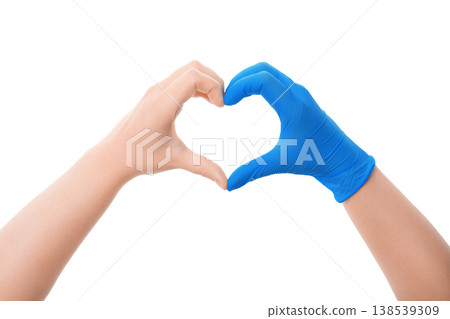 Two hands forming a heart shape, one bare and one in a blue medical glove, isolated on white. Symbolizes love, compassion, medical care, and gratitude to healthcare workers. Two hands forming a heart shape, one bare and one in a blue medical glove, isolated on white. Symbolizes love, compassion, medical care, and gratitude to healthcare workers. 138539309