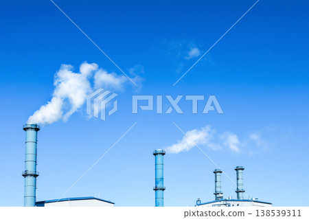 White smoke rises from blue industrial smokestacks against a clear sky, highlighting themes of thermal electricity, pollution, and the global energy crisis. White smoke rises from blue industrial smokestacks against a clear sky, highlighting themes of thermal electricity, pollution, and the global energy crisis. 138539311