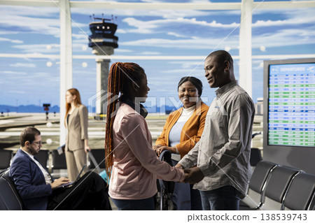 Teenager traveling alone, father hugging as goodbye, airport terminal lounge, daughter boarding the plane and flying abroad leaving single parent behind. African american small family. Teenager traveling alone, father hugging as goodbye, airport terminal lounge, daughter boarding the plane and flying abroad leaving single parent behind. African american small family. 138539743