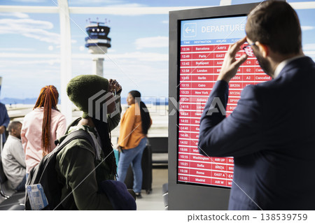 Diverse people in crisis panicking in airport terminal after all flights cancelled, shown in red on departures information board. Travelers appear angry by disrupted travel plans, bad news. Diverse people in crisis panicking in airport terminal after all flights cancelled, shown in red on departures information board. Travelers appear angry by disrupted travel plans, bad news. 138539759