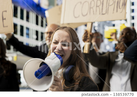 Gen z young adult with loudspeaker attends political rally marching against corruption and bad governing, raising signs for equality and anti-censorship. Awareness through serious political activism. Gen z young adult with loudspeaker attends political rally marching against corruption and bad governing, raising signs for equality and anti-censorship. Awareness through serious political activism. 138539770