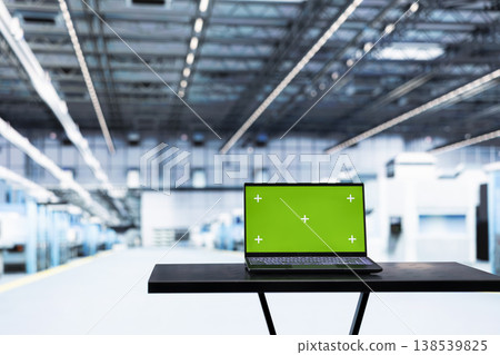 Green screen laptop in empty microchip factory used for testing silicon wafer batches with control application. Mockup notebook monitoring semiconductor manufacturing plant machinery readouts 138539825