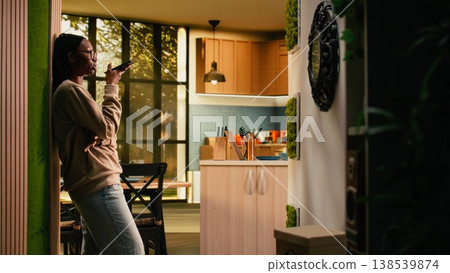 African american girl answering mobile phone call and putting it on speaker, comfortable lifestyle with soft light and warmth. Woman relaxing at home with a friend on remote chat, lifestyle. African american girl answering mobile phone call and putting it on speaker, comfortable lifestyle with soft light and warmth. Woman relaxing at home with a friend on remote chat, lifestyle. 138539874