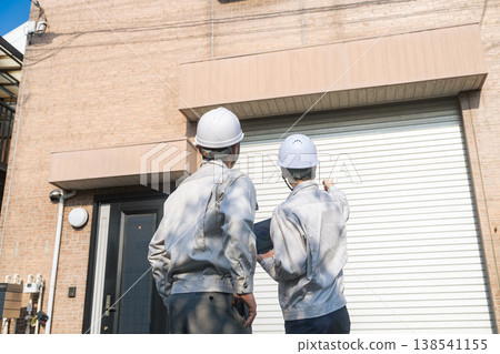 A group of male workers inspecting a house. A group of male workers inspecting a house. 138541155
