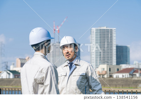 A group of male workers talking in front of a city A group of male workers talking in front of a city 138541156