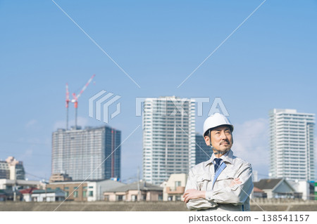 A male worker gazes into the distance in front of a city. A male worker gazes into the distance in front of a city. 138541157