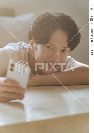 A young man who uses a smartphone with a smile A young man who uses a smartphone with a smile 138541163