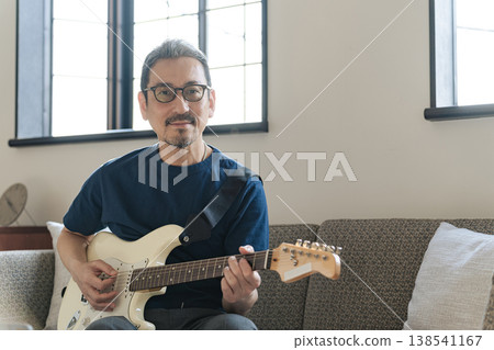 A middle-aged man playing the guitar. A middle-aged man playing the guitar. 138541167