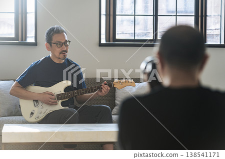 A photographer photographs a middle-aged man playing the guitar. 138541171