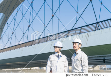 A group of male workers standing in front of the bridge 138541200