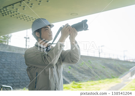 A male worker photographs the facility with a camera. A male worker photographs the facility with a camera. 138541204