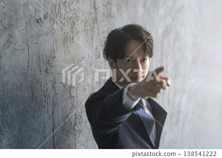 A young male businessperson points upwards. A young male businessperson points upwards. 138541222
