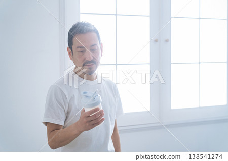 A middle-aged man holding a protein bottle. A middle-aged man holding a protein bottle. 138541274