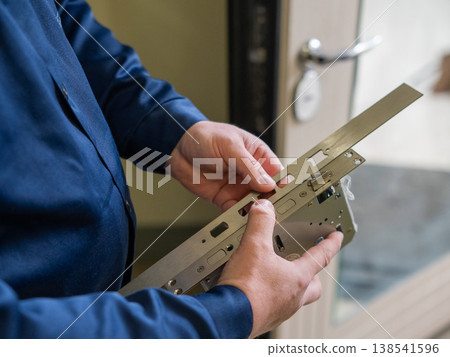 The technician installs a smart electronic lock on the front door. 138541596