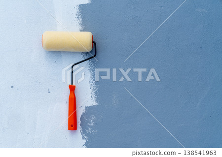 Yellow paint roller with red handle applying blue paint to a light textured wall. Concept of home renovation, interior design, and diy home improvement projects with copy space on the right. Yellow paint roller with red handle applying blue paint to a light textured wall. Concept of home renovation, interior design, and diy home improvement projects with copy space on the right. 138541963
