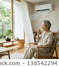 An elderly woman coolly drinks water in a comfortable, air-conditioned room. 138542294