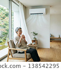 An elderly woman coolly drinks water in a comfortable, air-conditioned room. 138542295