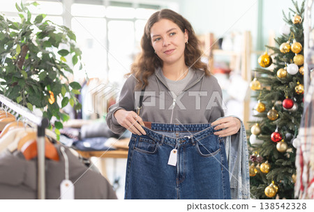 woman chooses high quality jeans against the background of a Christmas tree woman chooses high quality jeans against the background of a Christmas tree 138542328