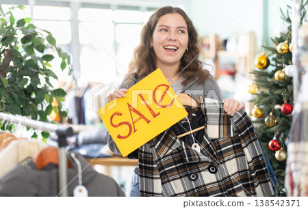 Young woman holding sale sign in clothing store 138542371