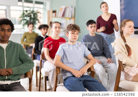 During meeting at class, teen pupil listen to lecture, female teacher in background. During meeting at class, teen pupil listen to lecture, female teacher in background. 138542398