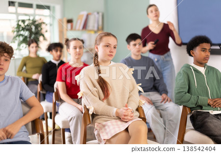 Teenage students listening to lecture while teacher stands in background 138542404