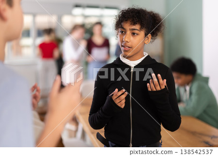 Teenage girl talking to classmate in classroom Teenage girl talking to classmate in classroom 138542537
