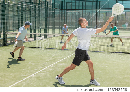 Men play padel on an outdoor tennis court. Hitting the ball with racket Men play padel on an outdoor tennis court. Hitting the ball with racket 138542558
